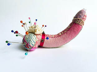 Lavender stuffed, penis shaped pin cushion in floral fabrics with swarovski crystals.